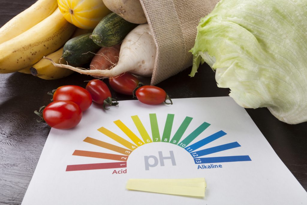 pH strips arranged in a rainbow pattern with produce.