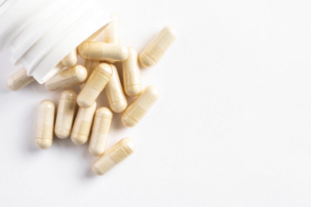 Dietary supplement gel capsules with a white bottle and white background