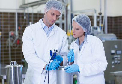 A man and a woman standing together and inspecting equipment in a food factory to demonstrate food safety culture.