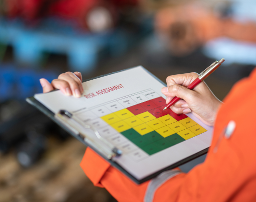 Risk assessment matrix grid on a clipboard with a person holding a pen to fill it out.
