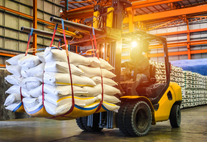 Forklift transporting stacked white food ingredient bags in a warehouse