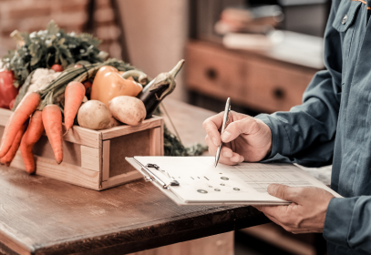 person checking off a checklist in a kitchen with produce on the table.