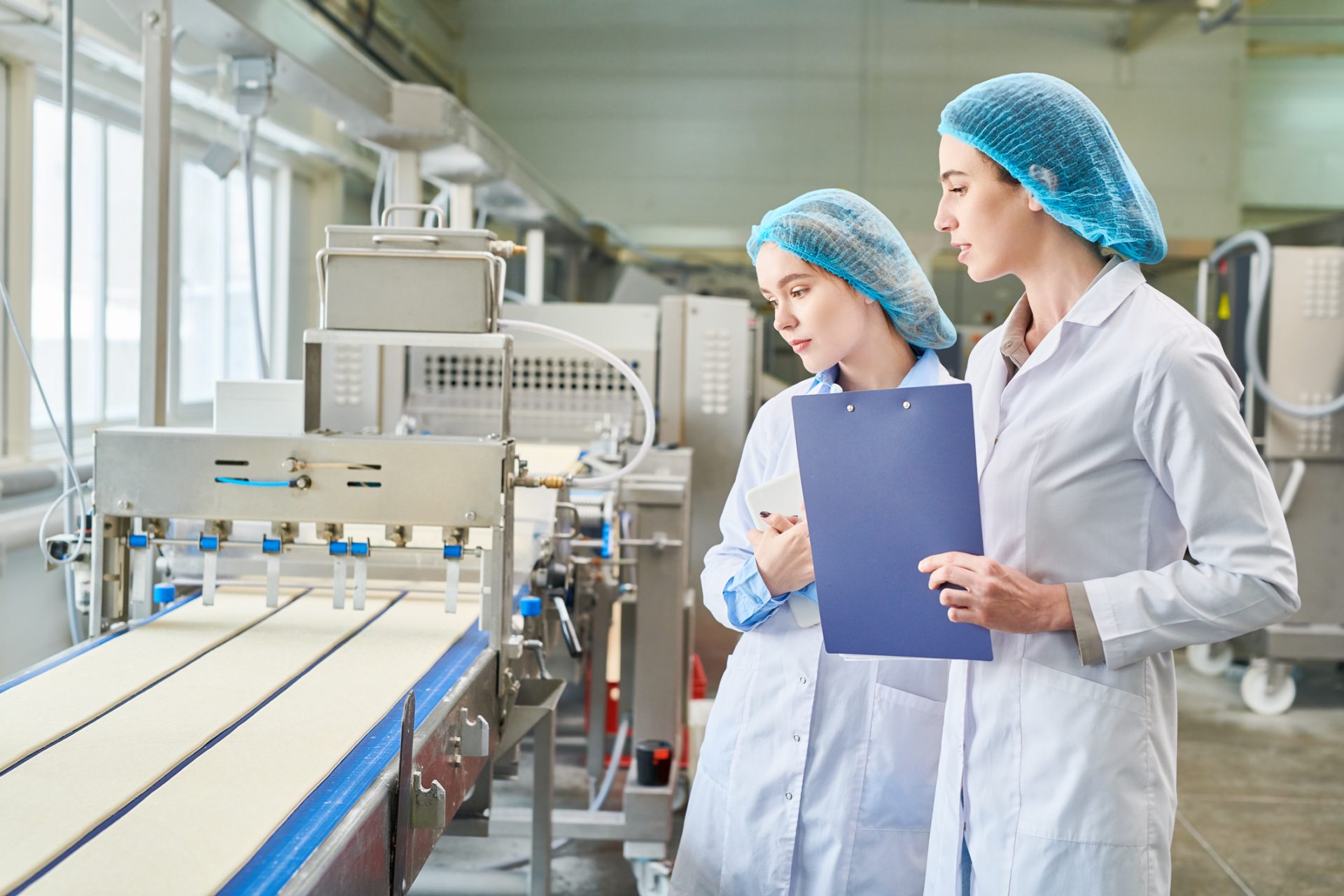 Two women inspecting food manufacturing equipment to validate and verify food safety programs.